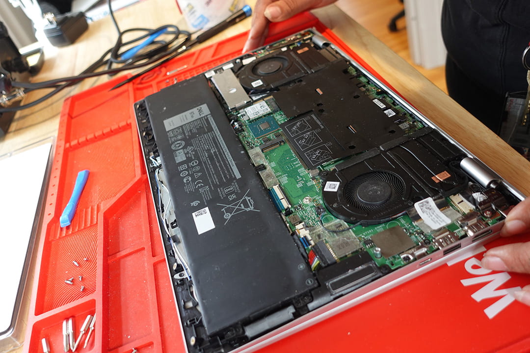 A laptop with its internal components visible, sitting on top of a red silicone mat
